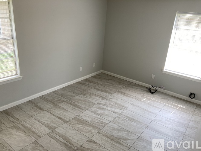 A room with a tiled floor and two windows.