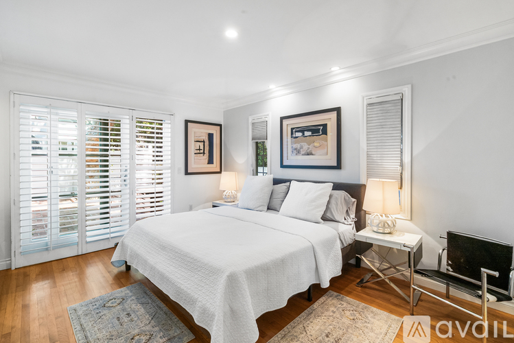 A bedroom with a large bed, a chair, and a small table with a lamp on it.
