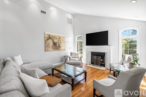 A living room with a grey couch, a glass coffee table, a fireplace, and a painting on the wall.