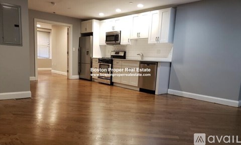 A kitchen area with wooden floors and a countertop with a microwave and oven.