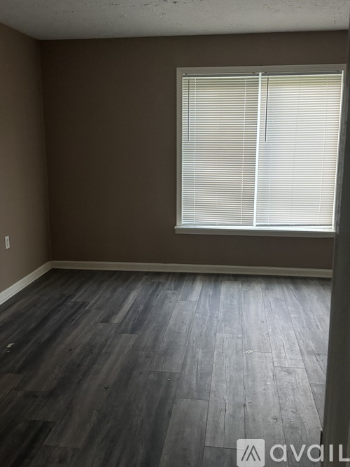 A room with a window and wooden flooring.