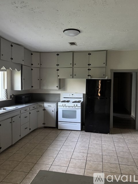 A kitchen with white cabinets and a black fridge.