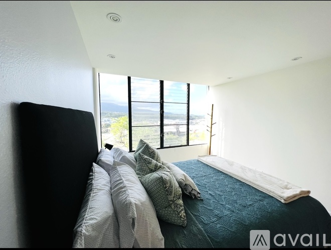 A bedroom with a large bed and a view of the outdoors through the window.
