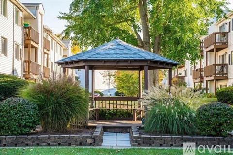 A gazebo is surrounded by a small garden and apartment buildings.