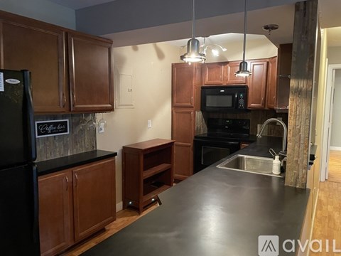 A kitchen with brown cabinets and a black refrigerator.