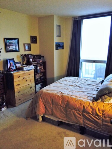 A bedroom with a bed, dresser, and window.