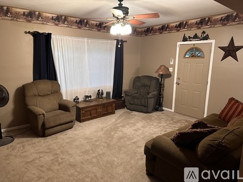 A living room with two recliners, a table with a lamp, and a ceiling fan.