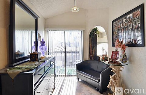 A living room with a black couch and a framed picture on the wall.