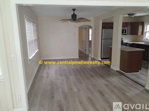 A spacious living room with a ceiling fan and lighting fixture.