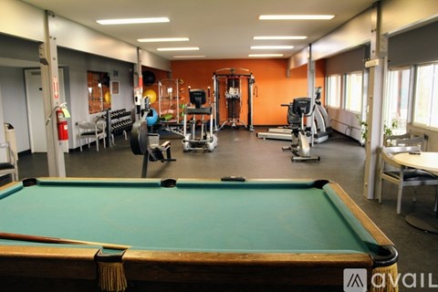 A pool table is in the middle of a room with exercise equipment.