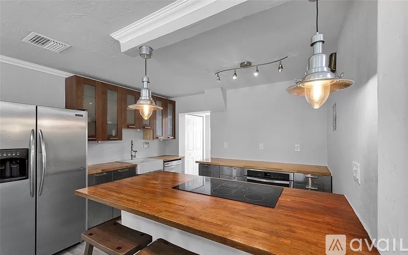A kitchen with a wooden island and stainless steel appliances.