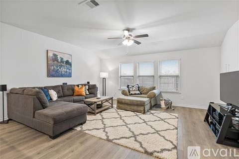 A living room with a grey couch and a painting on the wall.