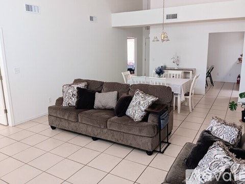 A living room with a brown couch and a white dining table.