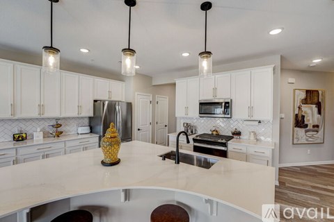 A kitchen with white cabinets and a large island with a vase on it.