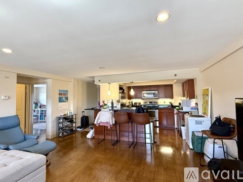 A living room with a blue chair and a kitchen in the background.