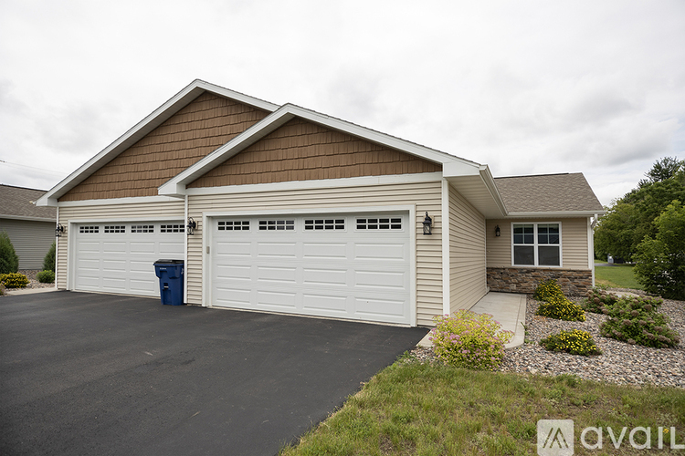 A two-car garage with a blue trash bin in front.