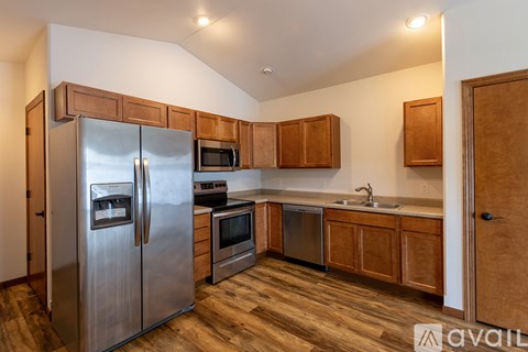 A kitchen with wooden cabinets and a stainless steel refrigerator.