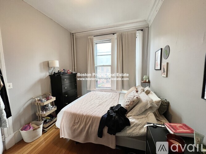 A bedroom with a bed, nightstand, and window.