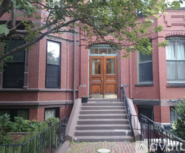 A red brick building with a wooden door and stairs leading up to it.