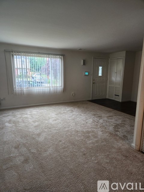 A room with a carpeted floor and a window with blinds.