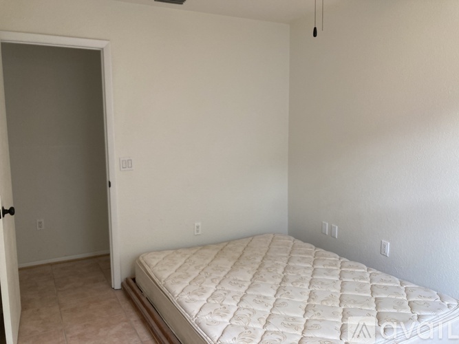 A bedroom with a bed, carpeted floor, and a door.