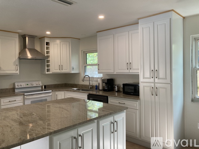 A kitchen with white cabinets and a granite countertop.