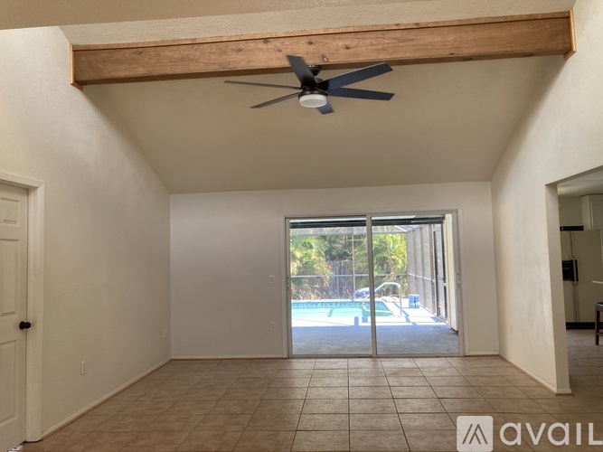 A room with a ceiling fan and sliding glass doors leading to a pool area.