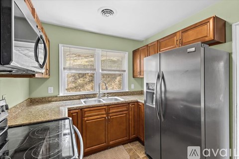 A kitchen with a stainless steel refrigerator and wooden cabinets.