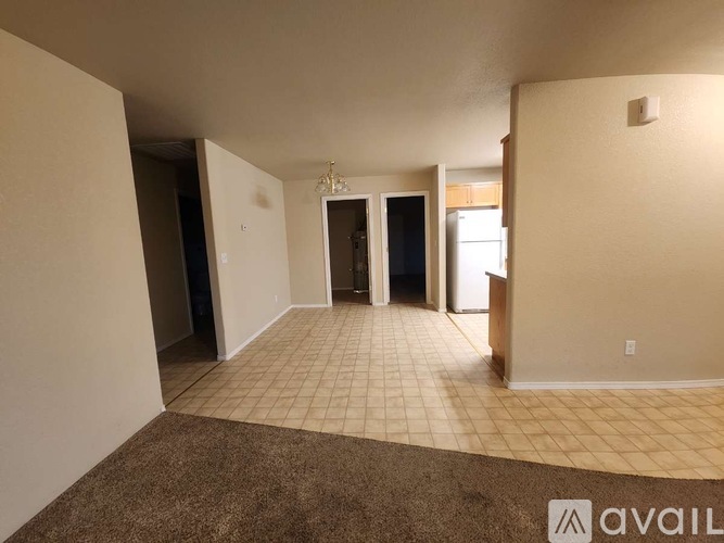 A spacious living room with a carpeted floor and a chandelier.