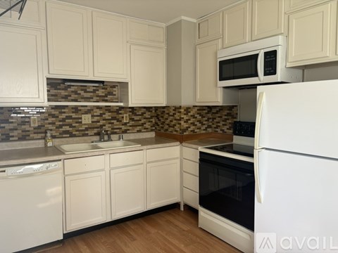 A kitchen with white cabinets and a black and white checkered backsplash.