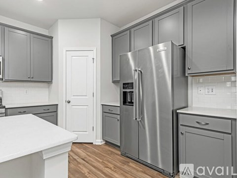 A kitchen with a stainless steel refrigerator and cabinets.