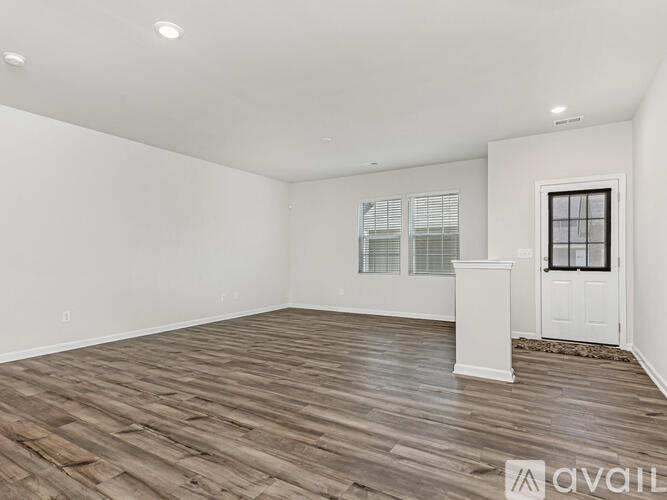 A spacious room with wooden flooring and white walls.