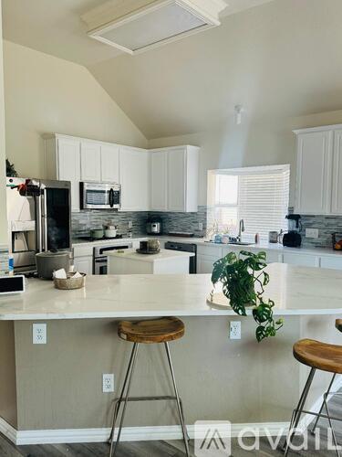 A kitchen with white cabinets and a countertop with a plant on it.