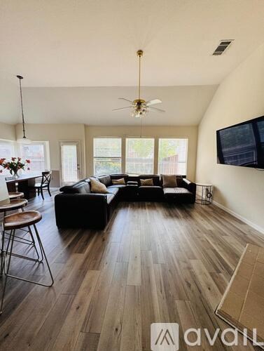 A living room with a black couch and a television mounted on the wall.