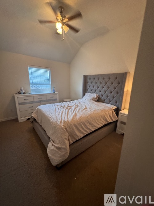 A bedroom with a bed, nightstand, and ceiling fan.
