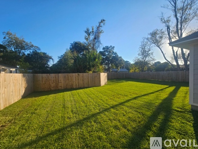 A backyard with a wooden fence and green grass.