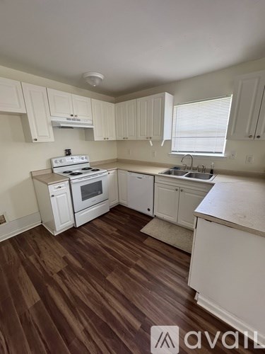 A kitchen with white cabinets and a wood floor.