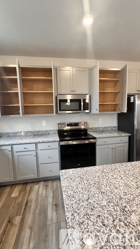 A kitchen with a black stove top oven and white cabinets.