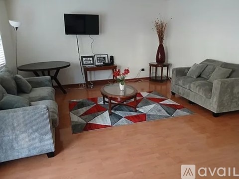 A living room with a grey couch, a coffee table, and a flat screen TV.