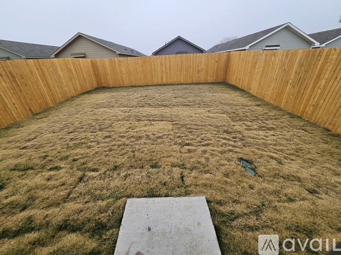 A backyard with a wooden fence and a concrete slab in the foreground.