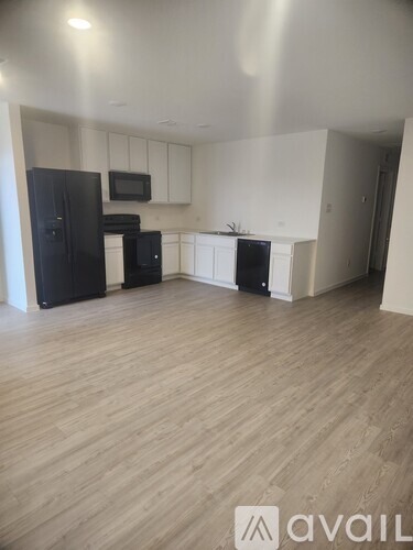 A kitchen with black appliances and wooden floors.