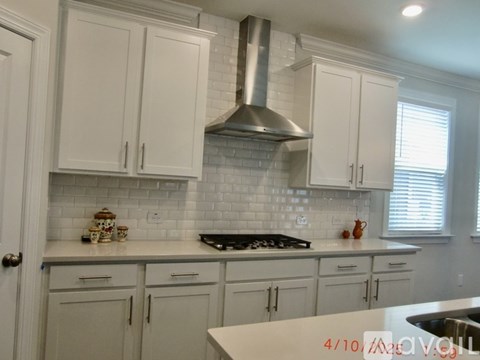 A kitchen with white cabinets and a stainless steel range hood.