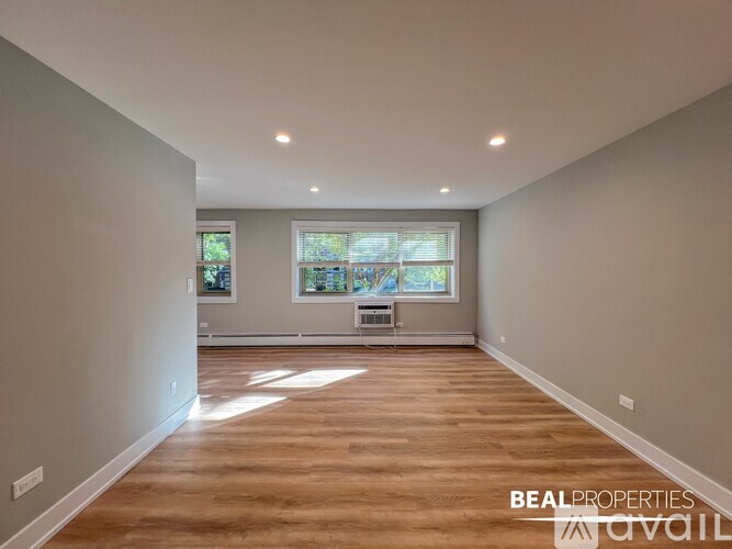 A spacious room with wooden flooring and a window seat.