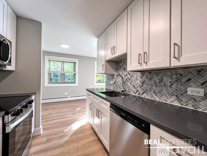 A kitchen with a black counter top and stainless steel appliances.