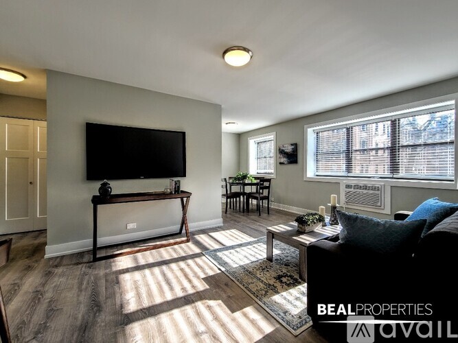 A living room with a flat screen TV mounted on the wall and a black sofa.