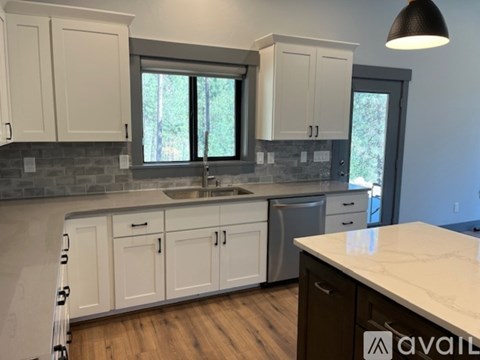 A kitchen with white cabinets and a marble countertop.