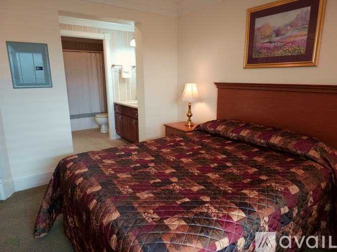 A bedroom with a large bed and a painting on the wall.