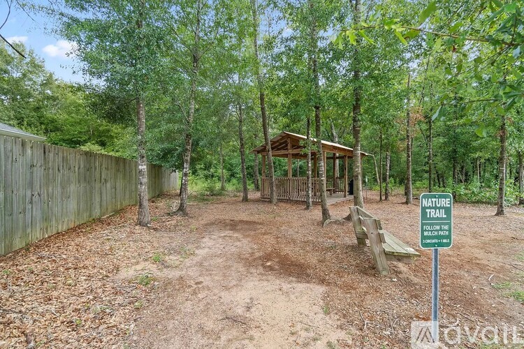 A nature trail sign is in front of a wooden fence and trees.