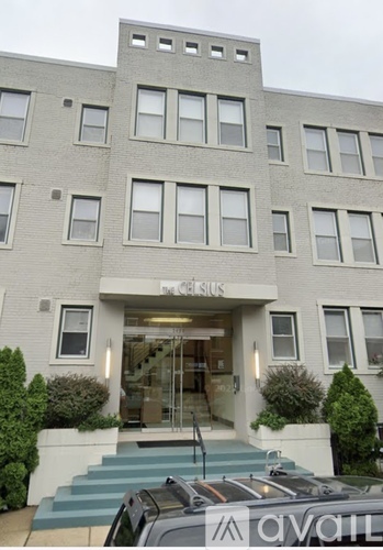A grey building with a glass entrance and a car parked in front.