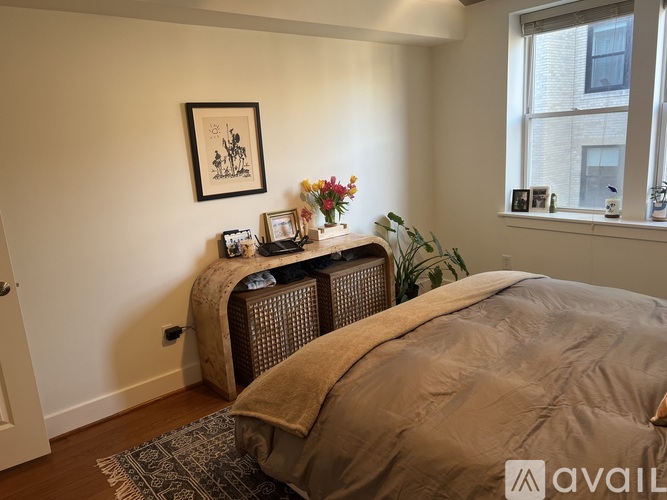 A bedroom with a bed, a window, and a picture on the wall.